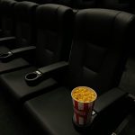 A bucket of popcorn in an empty cinema with black leather seats, creating a classic movie theater vibe.
