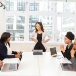 Diverse team engaged in a business meeting with laptops in a modern office setting.