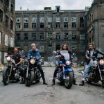 Four bikers in front of a graffiti-covered abandoned building, capturing urban lifestyle