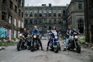 Four bikers in front of a graffiti-covered abandoned building, capturing urban lifestyle