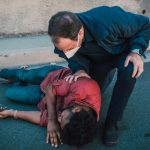 Paramedic aiding an injured man lying on the roadside, showcasing emergency care.